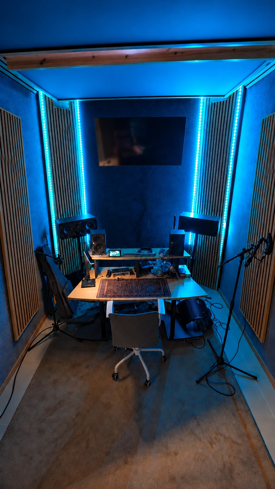 Regieplatz im Musikstudio mit Studiomonitoren, Mikrofon und blauem LED-Licht