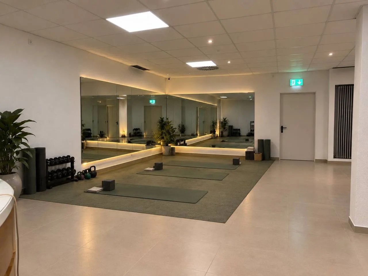 Sportecke mit beleuchteter Spiegelwand, Trainingsmatten und Kettlebells